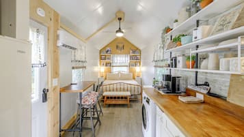 A compact, well-organized kitchen with a central island, a washing machine, and a coffee station.