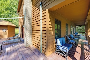 Une terrasse extérieure couverte, dotée d’un plancher en bois et de chaises rembourrées bleues.