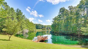 A serene lakeside setting with a wooden dock extending into the water, surrounded by lush greenery and trees. - Fishing Dock & Sauna! Farmville Gem w/ Views (Farmville)