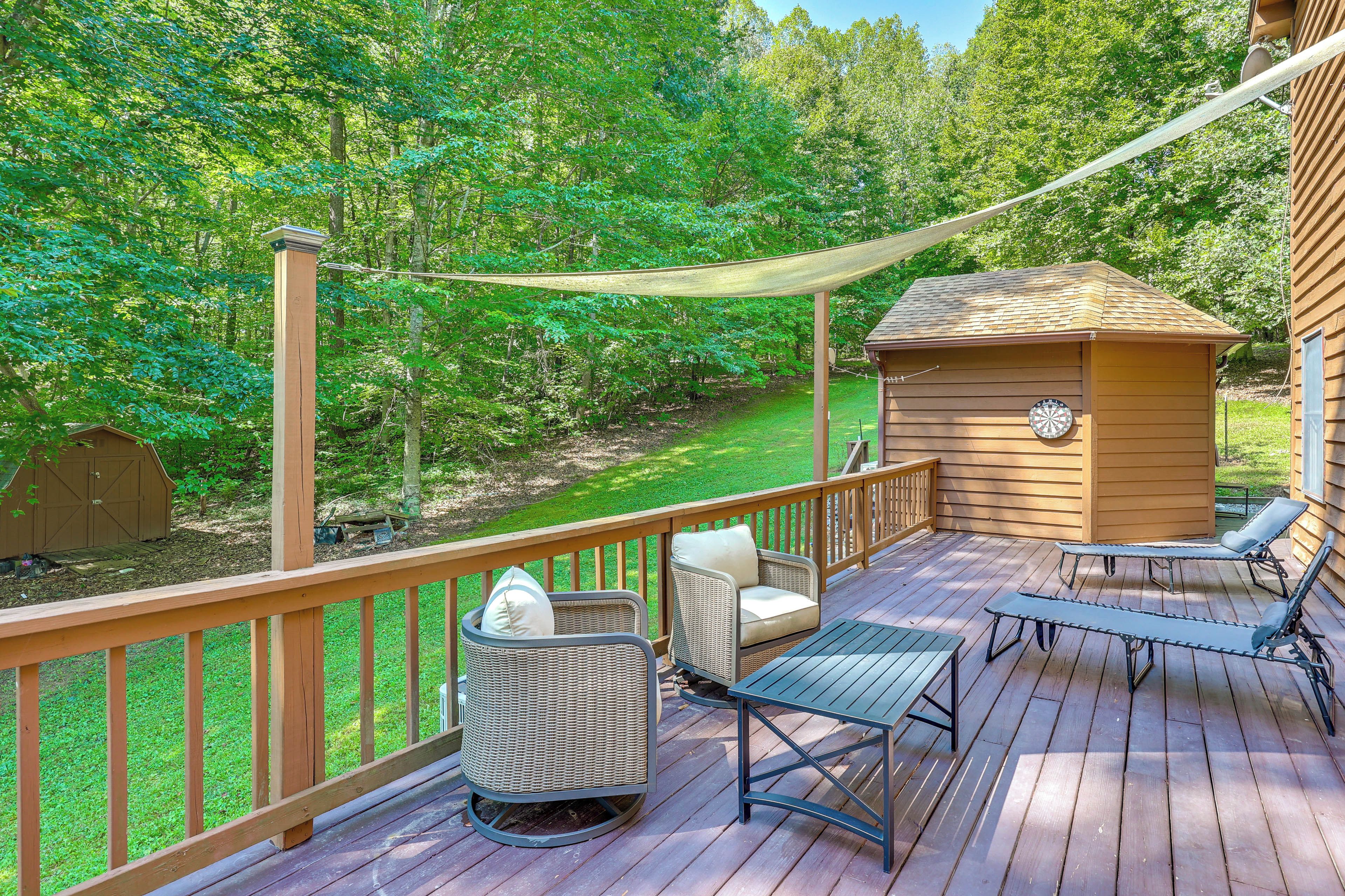 A wooden deck with outdoor furniture, a small shed, and a hammock.