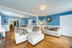 A living room with two sofas, a coffee table, a clock on the wall, and a door.