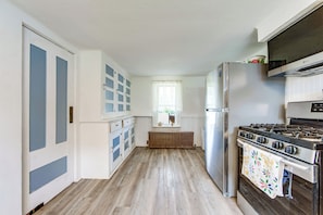 A kitchen with a stove, refrigerator, and cabinets.