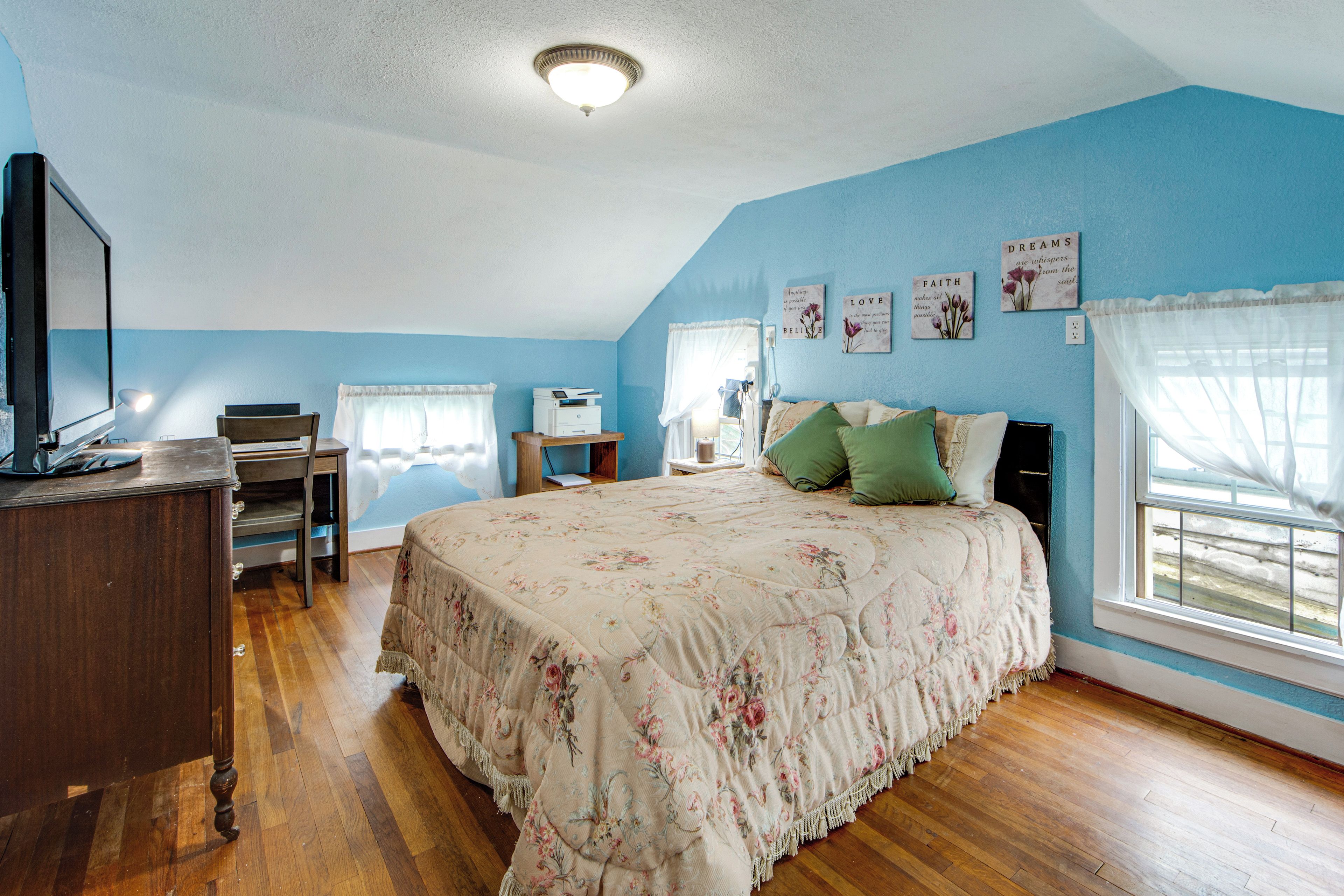A bedroom with a bed, a desk, a chair, and a television.