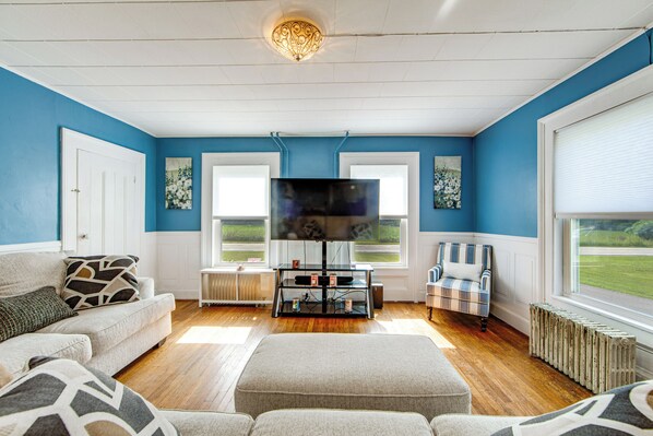 A living room with a television, a sofa, a chair, and a radiator.