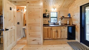 Ett träinredat utrymme med ett köksområde som inkluderar en diskho, skåp och ett kylskåp.