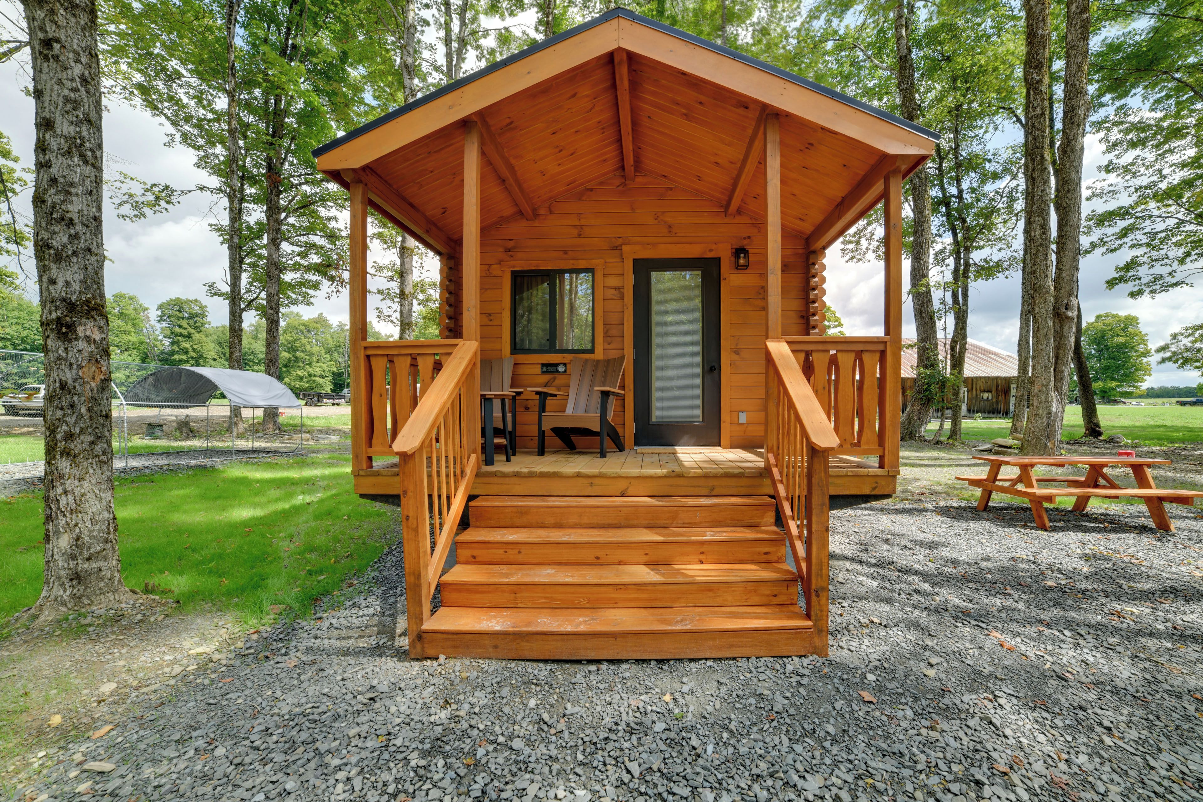 A wooden cabin with a porch, a door, and a window.