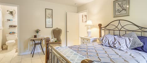 A bedroom with a bed, a desk, a chair, a nightstand, and a ceiling fan.