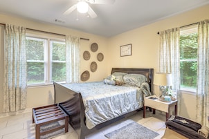 Un dormitorio con cama, mesita de noche, lámpara y una silla.