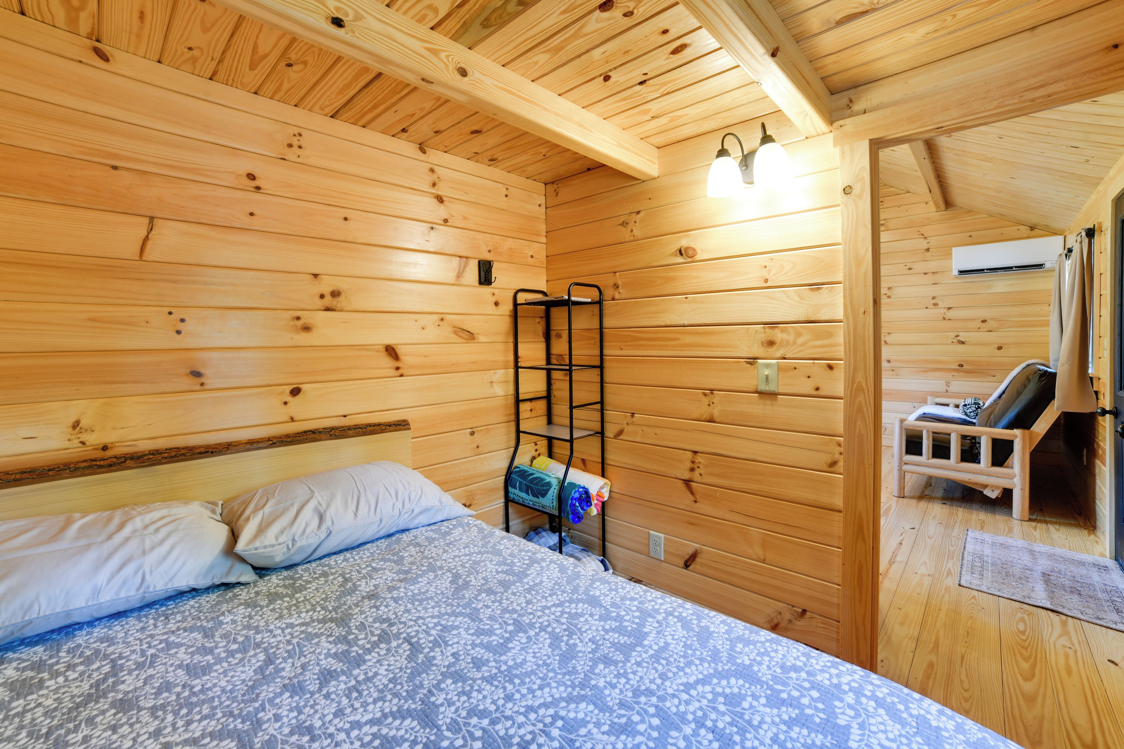 Una camera in legno con un letto, una panca e un lampadario.