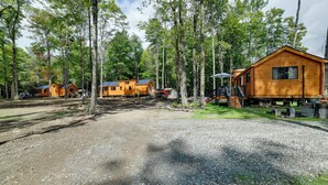 En campingplats med flera stugor byggda av trä, grusgångar och en skog som utgör bakgrunden.