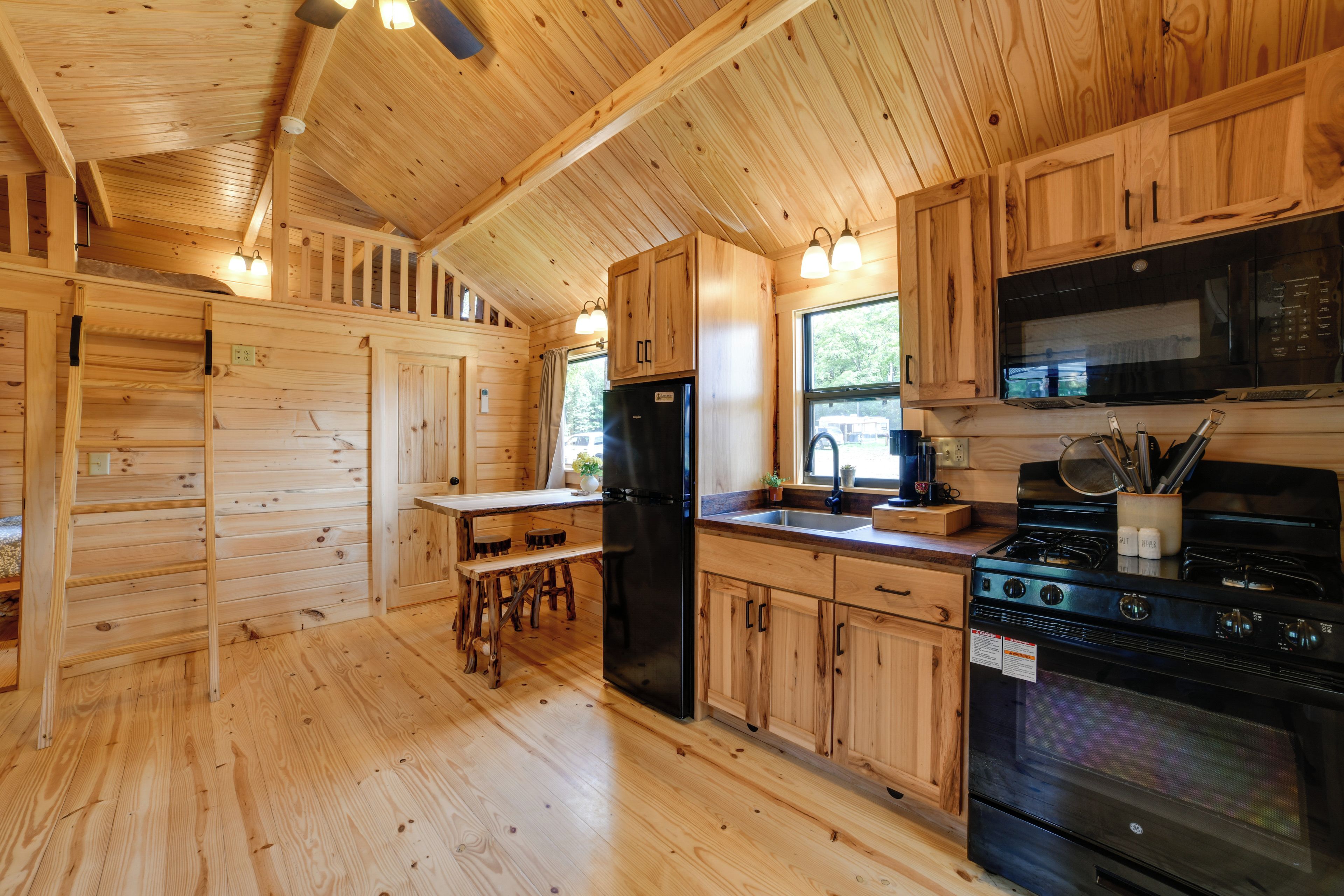 Interno di una baita in legno con angolo cottura, dotato di frigorifero, fornello e microonde.