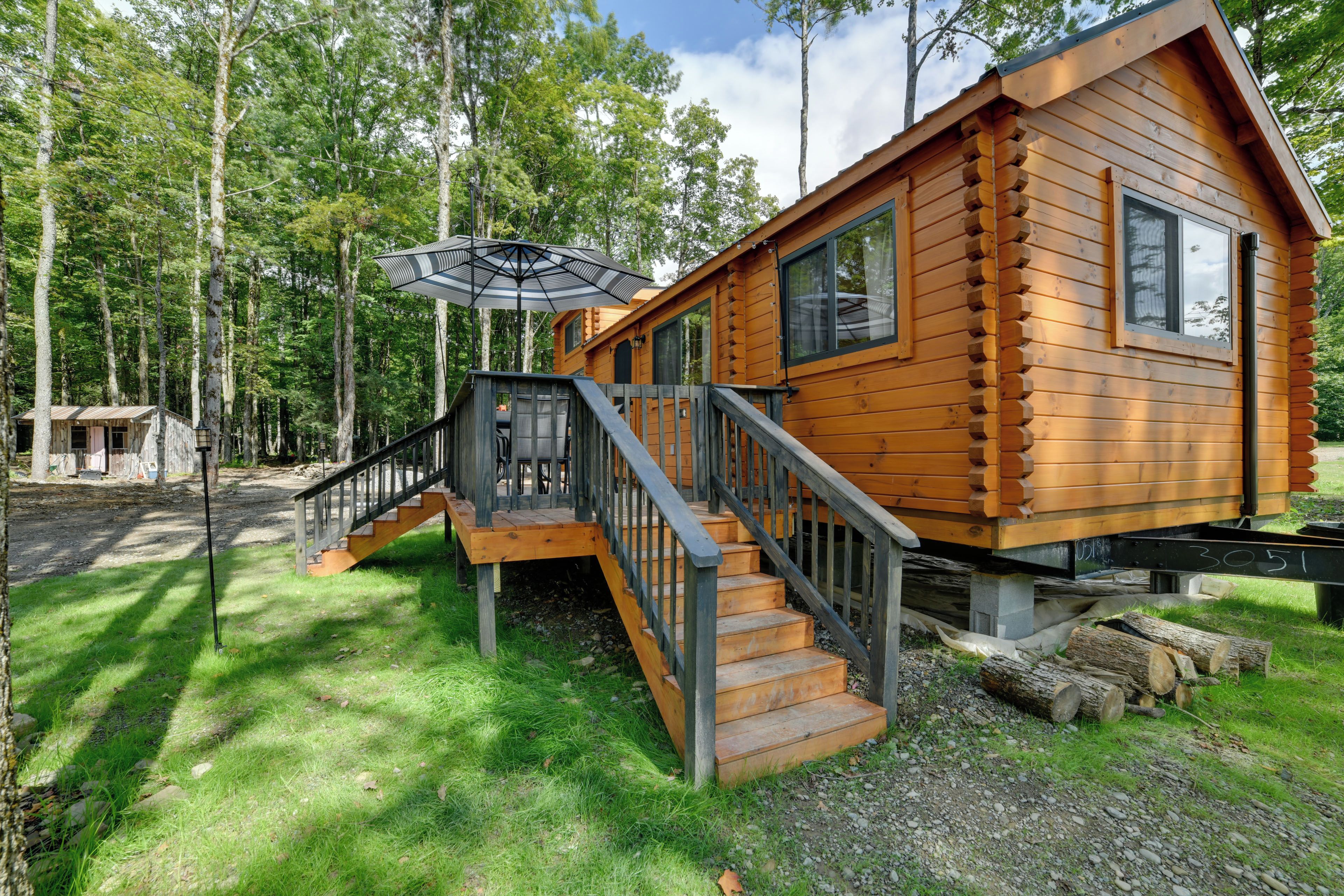 A wooden cabin with a staircase leading to a deck, surrounded by trees.