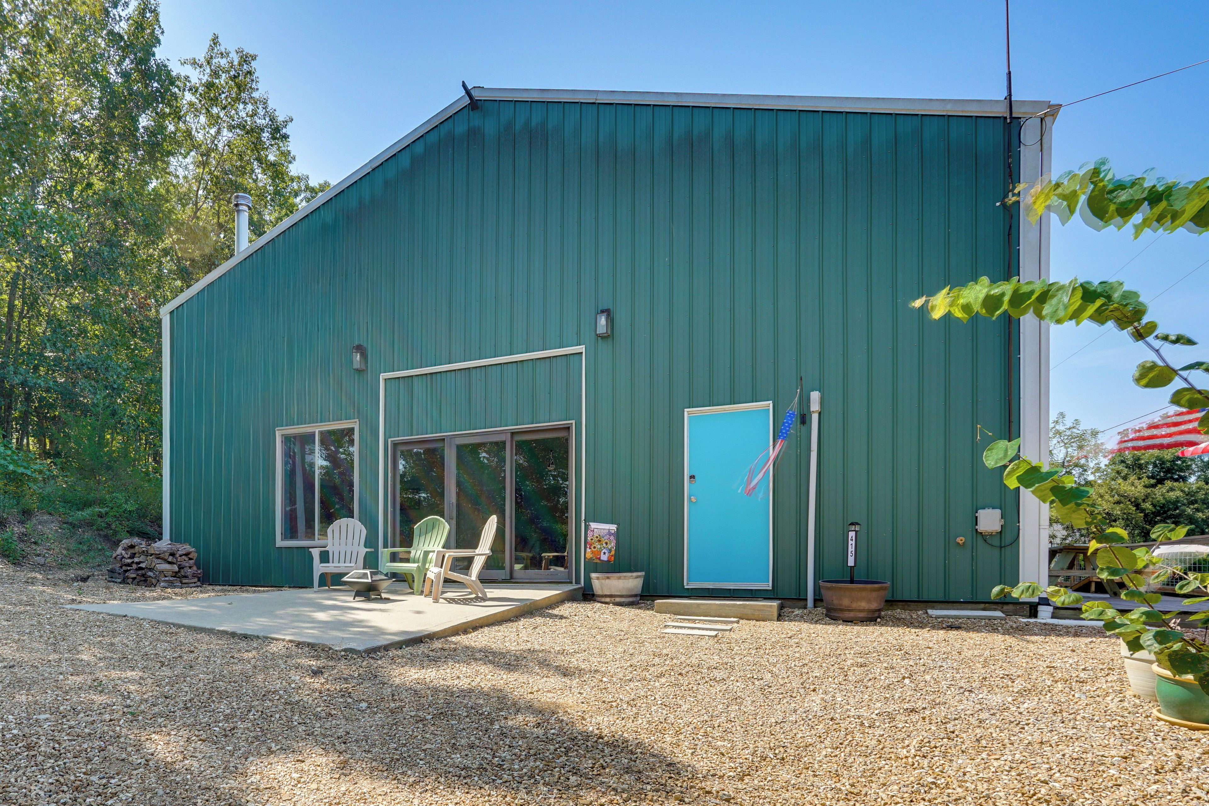 A green metal building with a patio area, two doors, and a flag.