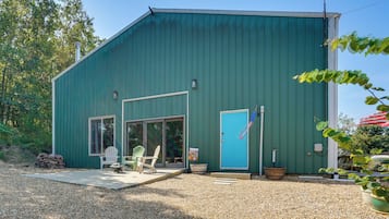 A green metal building with a patio area, two doors, and a flag.