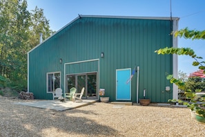 A green metal building with a patio area, two doors, and a flag. - Sunset Deck & Private Dock: Ozarks Lake House! (Edwards)