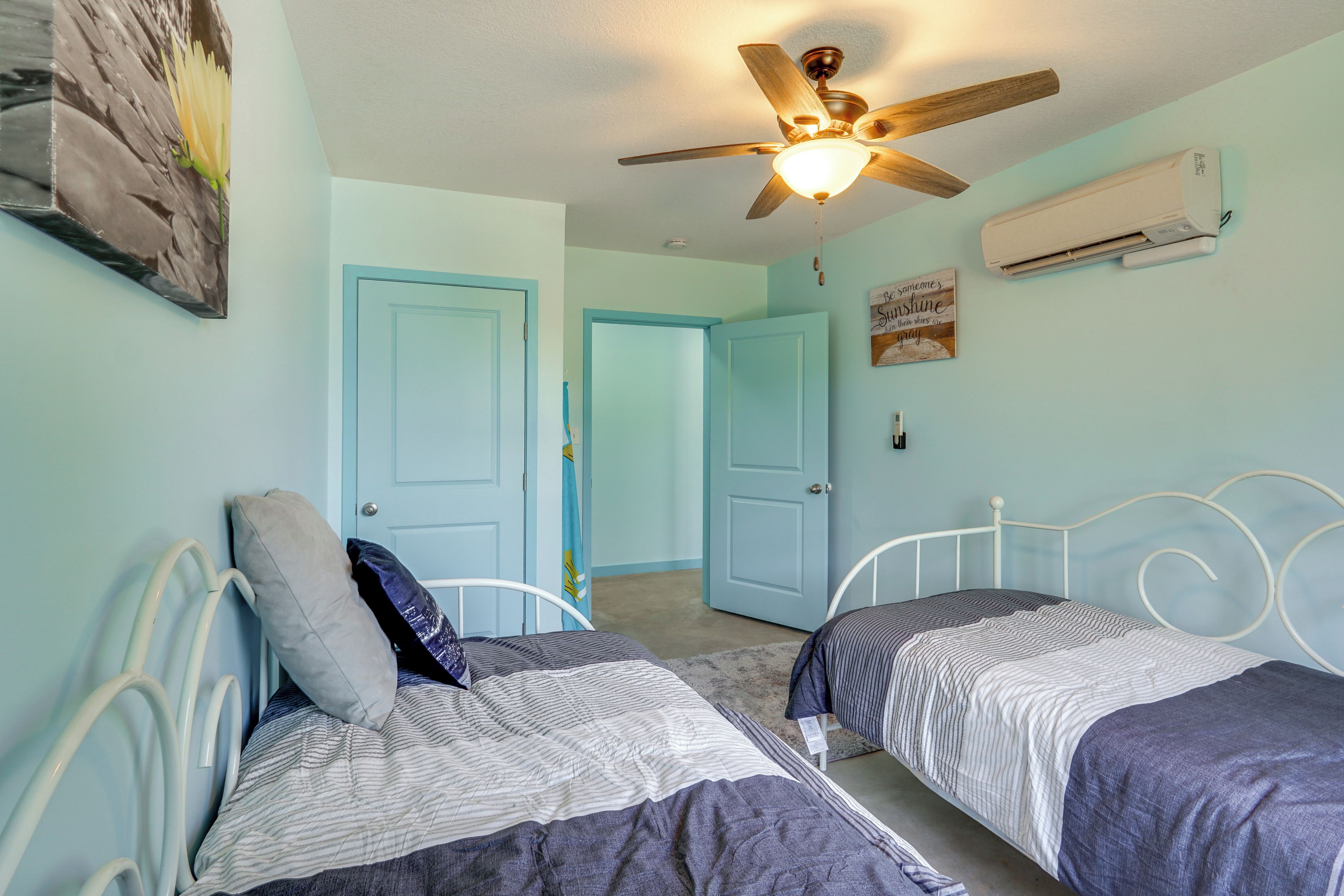 A bedroom with two beds, a ceiling fan, and an air conditioning unit.
