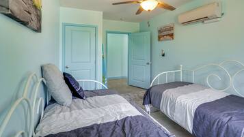 A bedroom with two beds, a ceiling fan, and an air conditioning unit.