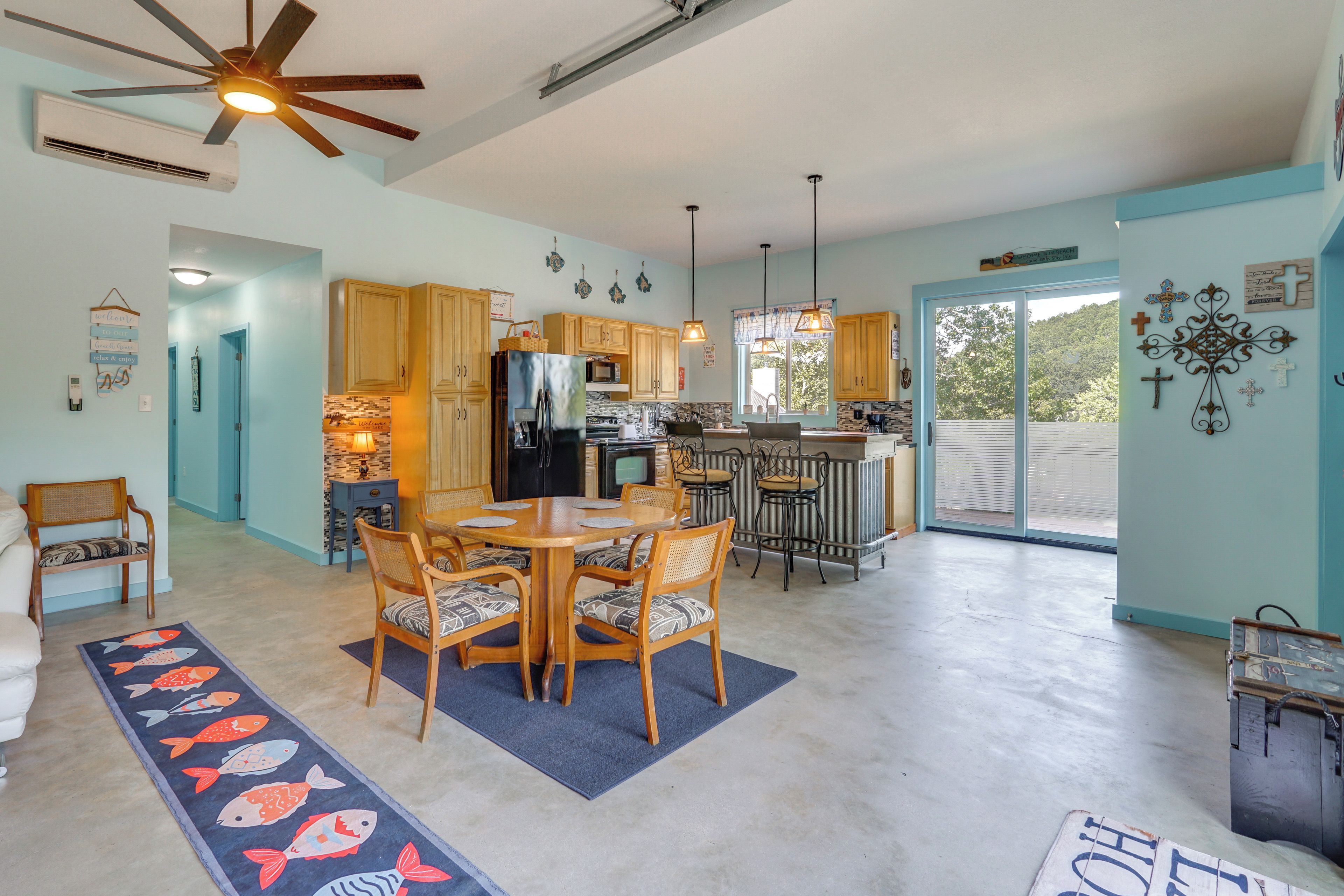 A spacious kitchen with wooden cabinets, a dining area with a table and chairs, and a ceiling fan.