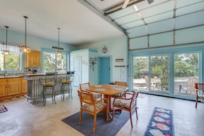 A spacious kitchen with wooden cabinets, a dining area with a round table and chairs, and a large sliding glass door leading to an outdoor patio. - Sunset Deck & Private Dock: Ozarks Lake House! (Edwards)