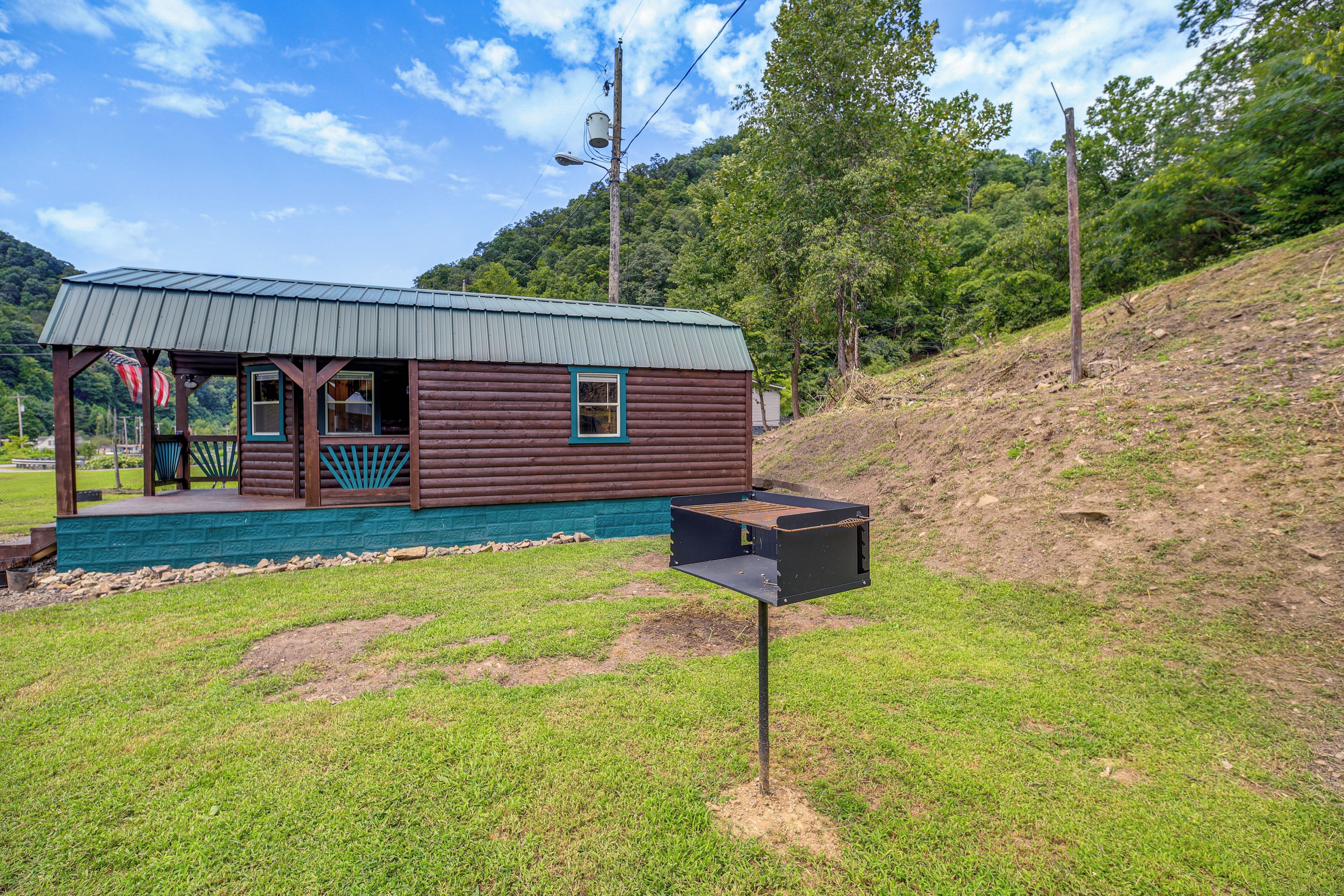 A rustic cabin with a porch, a mailbox, and a grassy area.