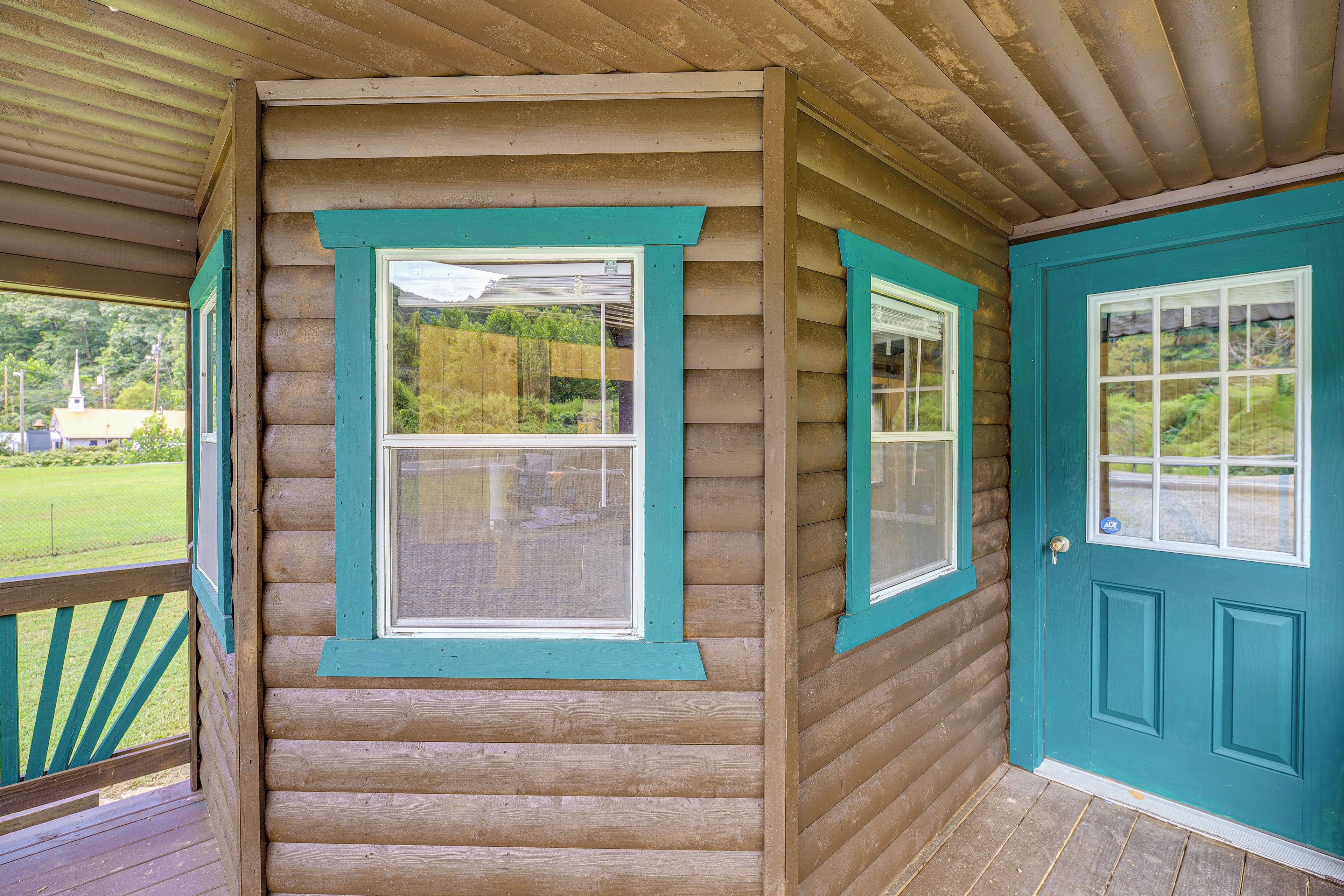 A log cabin with a porch, a door, and two windows.
