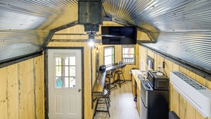 A compact kitchen with a sink, stove, and microwave, wooden walls, and a door with windows. - Near ATV Trails! Coal Heritage Cabin w/ Fire Pit (Roderfield)