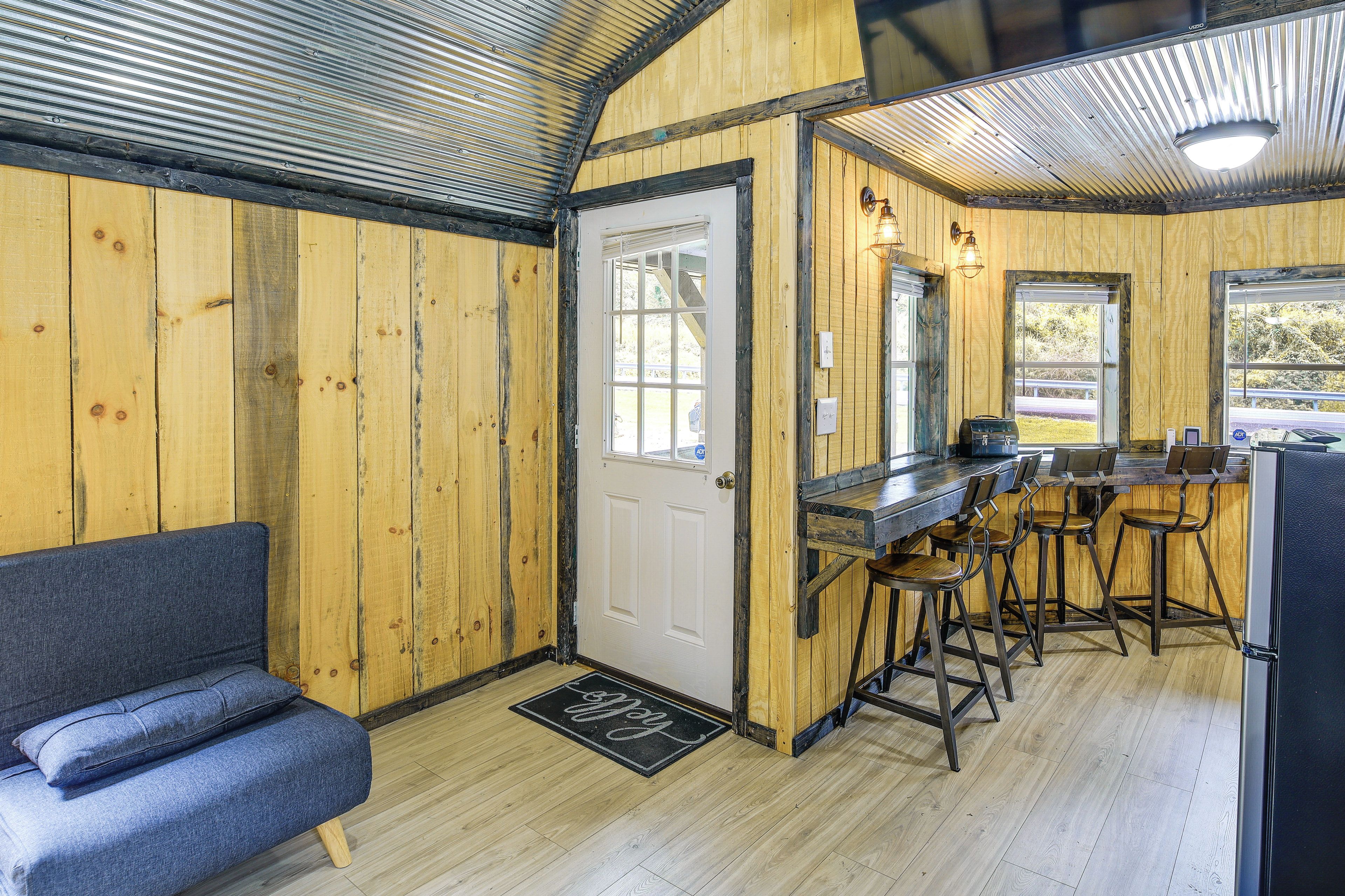A rustic interior with a wooden door, a bar area with stools, and a blue sofa.
