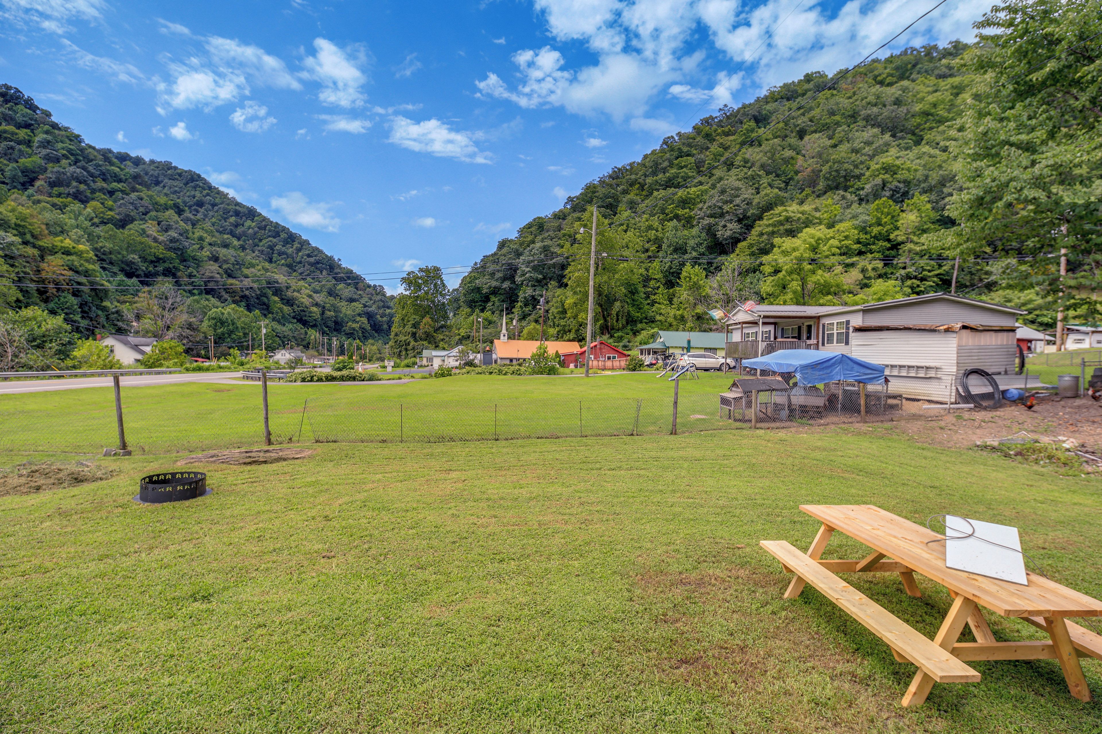 Um campo gramado com uma mesa de piquenique e um pequeno edifício com telhado de lona azul.