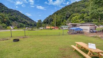 Um campo gramado com uma mesa de piquenique e um pequeno edifício com telhado de lona azul.