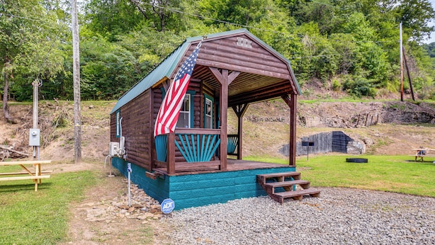 A small wooden cabin with a porch, an American flag, and a picnic table. - Near ATV Trails! Coal Heritage Cabin w/ Fire Pit (Roderfield)