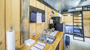 A compact room with a wooden interior, a sink, a coffee machine, and a bunk bed. - Near ATV Trails! Coal Heritage Cabin w/ Fire Pit (Roderfield)