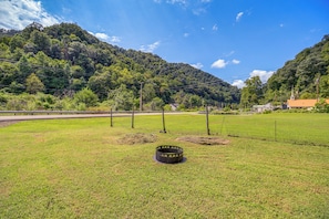 A grassy field with a metal structure, a road, and a mountain in the background.