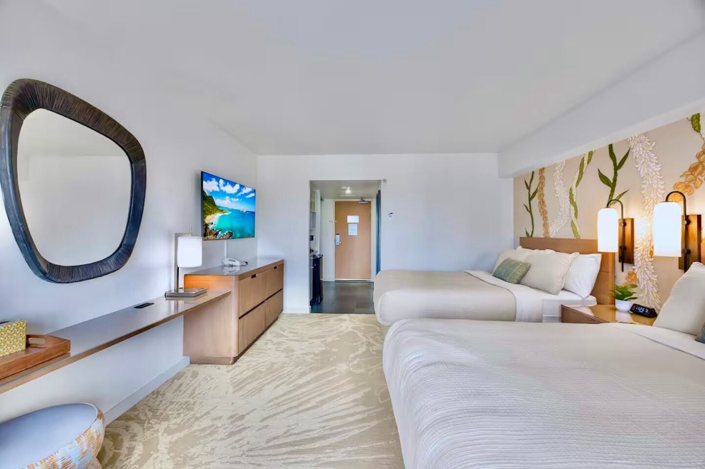 A hotel room with a bed, bedside table, lamp, and a large mirror.