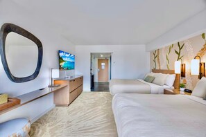 Una habitación de hotel con cama, mesita de noche, lámpara y un espejo grande.