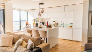 A modern living room with a sofa and a dining area with a kitchen in the background.