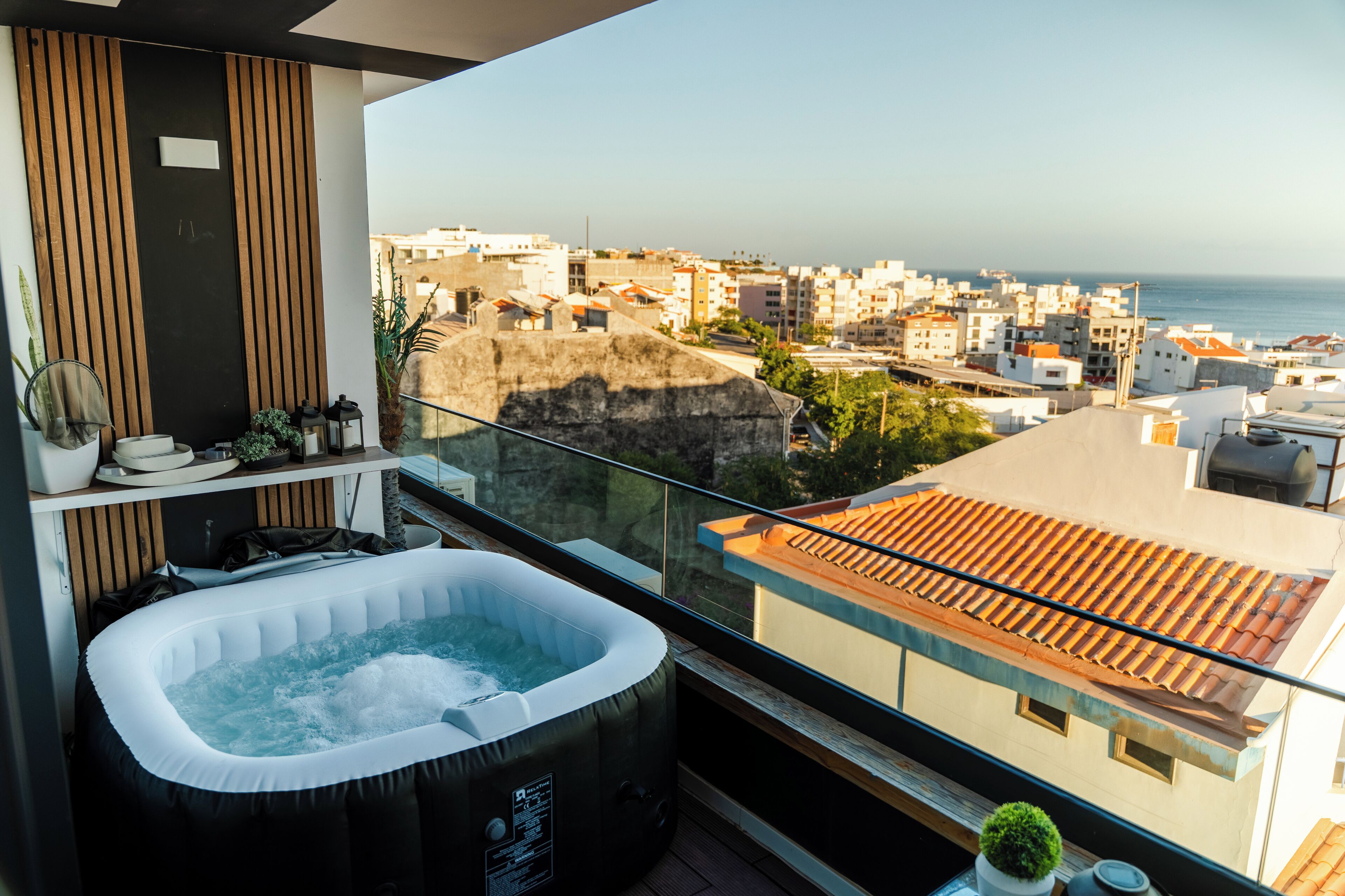 A balcony with a hot tub, a view of the cityscape, and a potted plant.