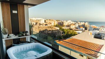 A balcony with a hot tub, a view of the cityscape, and a potted plant.