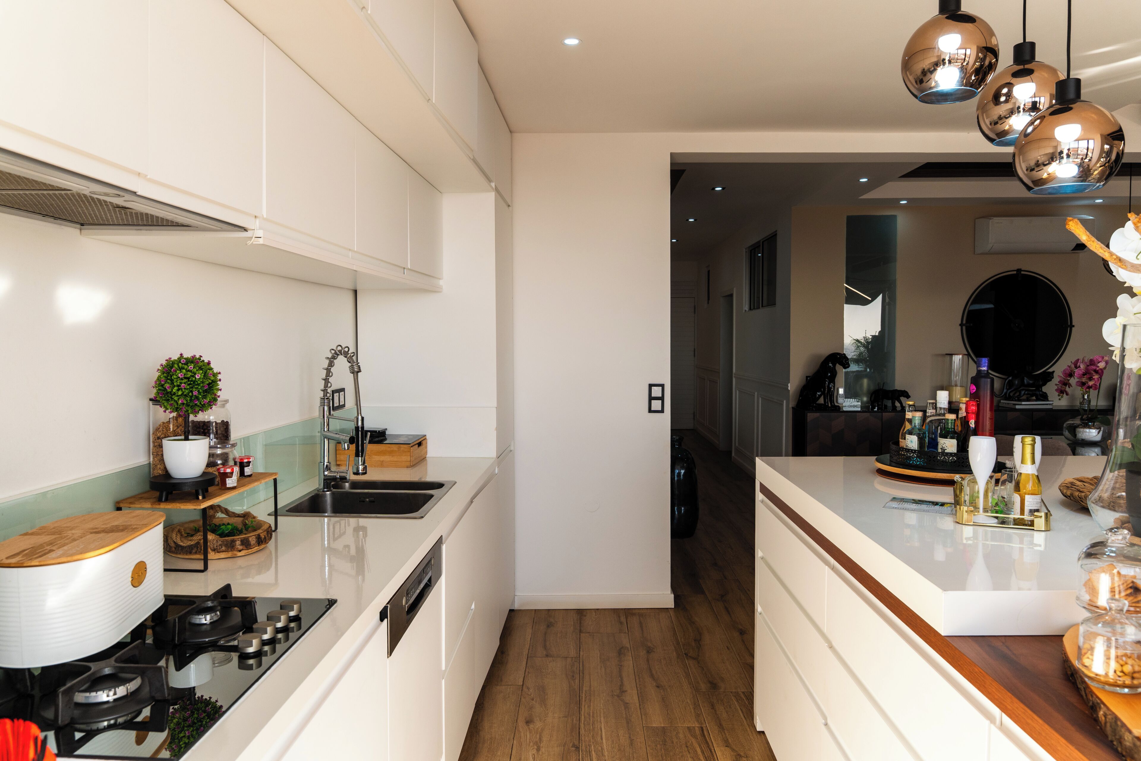 A modern kitchen with white cabinetry, a stainless steel sink, and a wooden countertop.