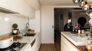 A modern kitchen with white cabinetry, a stainless steel sink, and a wooden countertop.