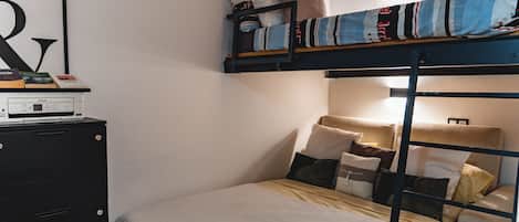 A bunk bed with pillows and a desk with a printer.