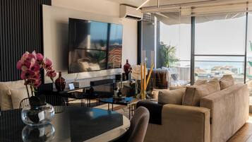 A modern living room with a flat-screen TV, a dining table, and a sofa.