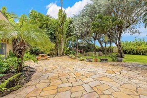 A stone patio with a wooden bench and potted plants.