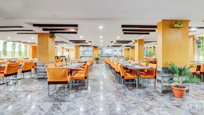 Un comedor amplio con varias mesas y sillas, piso de mármol y luz natural que entra por grandes ventanales.