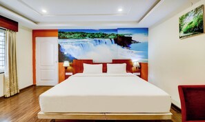 Ein Hotelzimmer mit einem großen Bett, einem Nachttisch mit Lampe, einer Tür und einem Wandbild eines Wasserfalls.