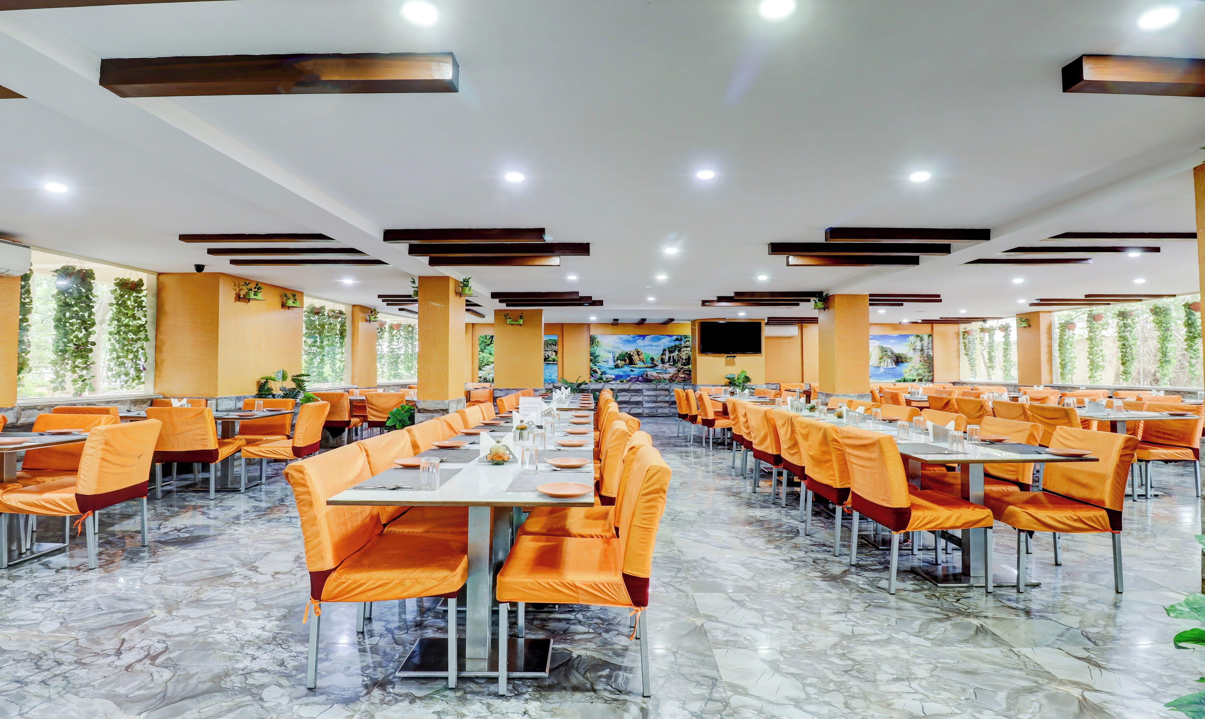 A spacious dining area with multiple tables and chairs, a marble floor, and a large mural on the wall.