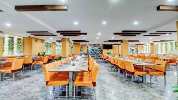 A spacious dining area with multiple tables and chairs, a marble floor, and a large mural on the wall.
