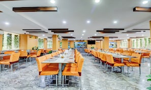 A spacious dining area with multiple tables and chairs, a marble floor, and a large mural on the wall.