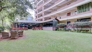Un edificio de varios pisos con un área de estar al aire libre techada, un spa y salón de belleza, y un gimnasio.