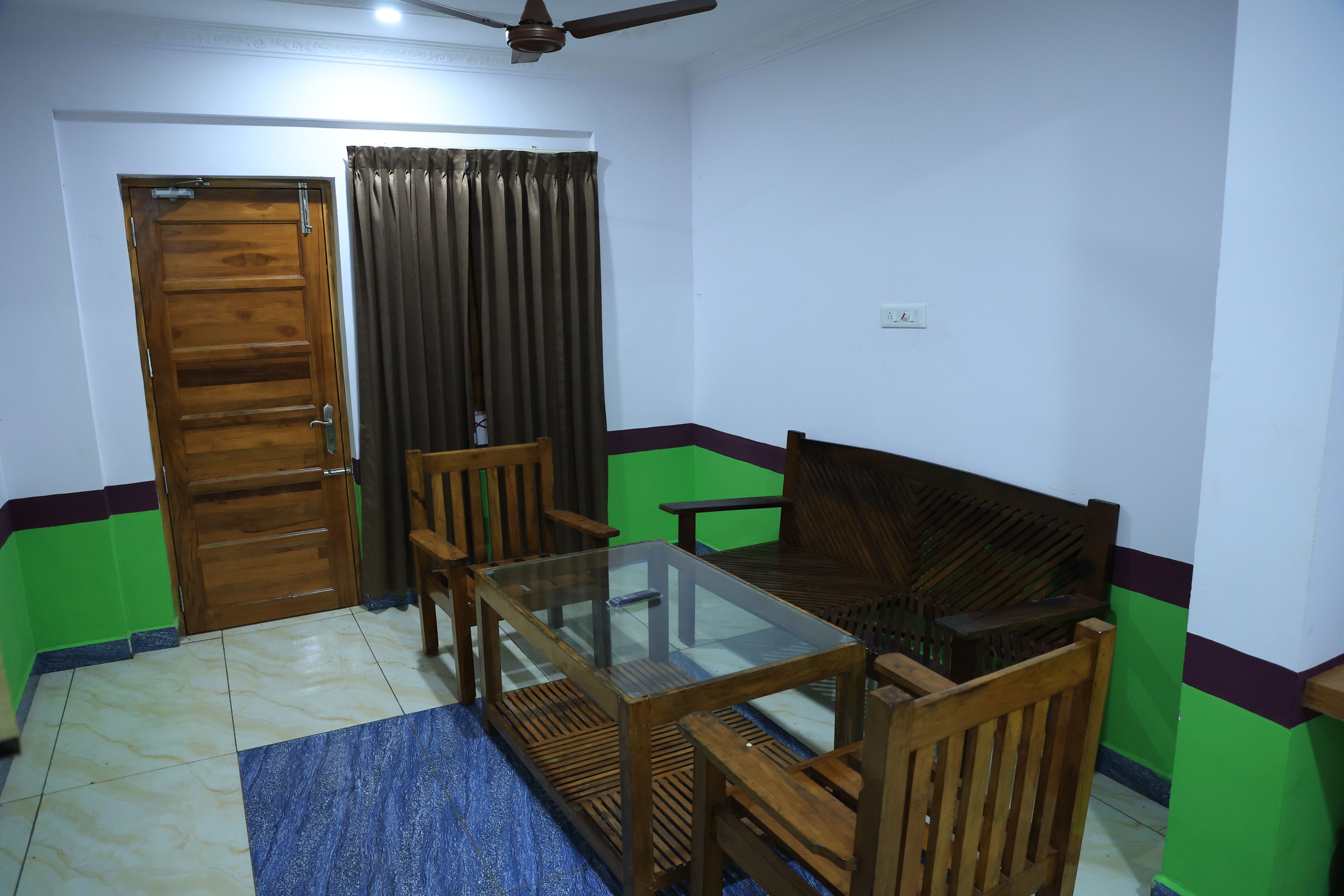 Una habitación con una puerta de madera, una mesa de vidrio y sillas de madera.