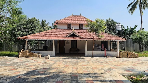 A two-story building with a tiled roof and a covered porch area. - Paisa Farm Stay (Pudunagar)